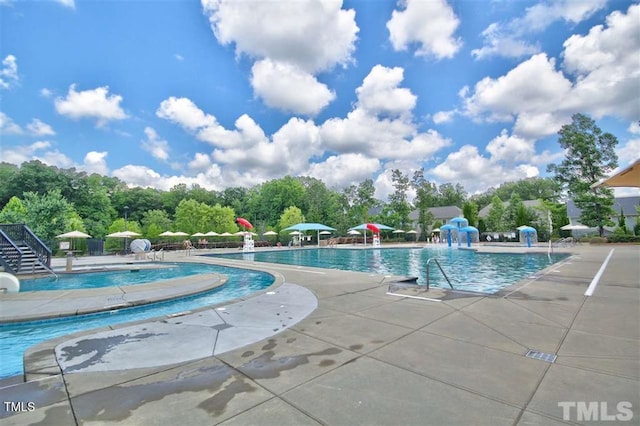 community pool with a patio area and a water slide