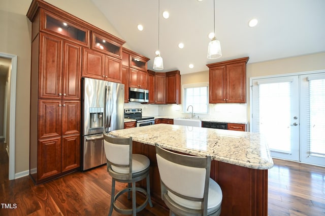 kitchen with vaulted ceiling, dark hardwood / wood-style floors, hanging light fixtures, a center island, and stainless steel appliances