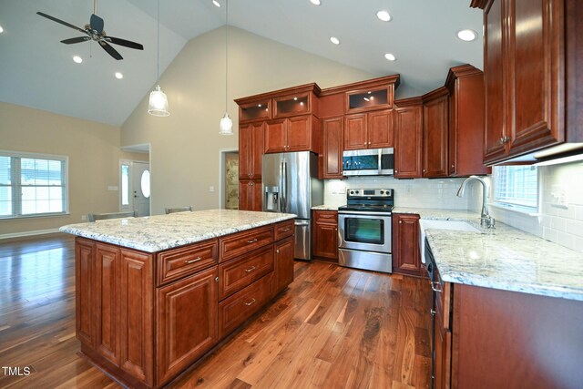 kitchen with a kitchen island, appliances with stainless steel finishes, sink, hanging light fixtures, and dark wood-type flooring