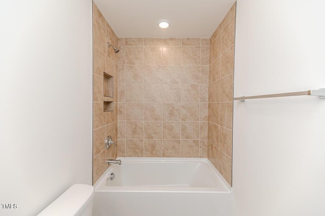 bathroom with toilet and tiled shower / bath