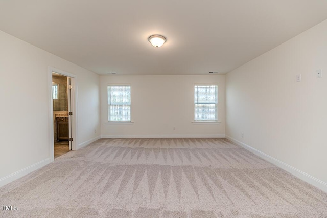 empty room featuring a wealth of natural light and light colored carpet