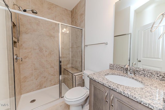 bathroom featuring toilet, vanity, and a shower with shower door