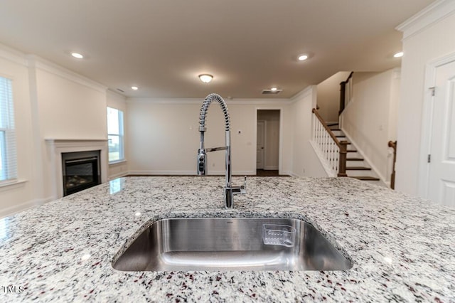 kitchen with sink, crown molding, and light stone counters