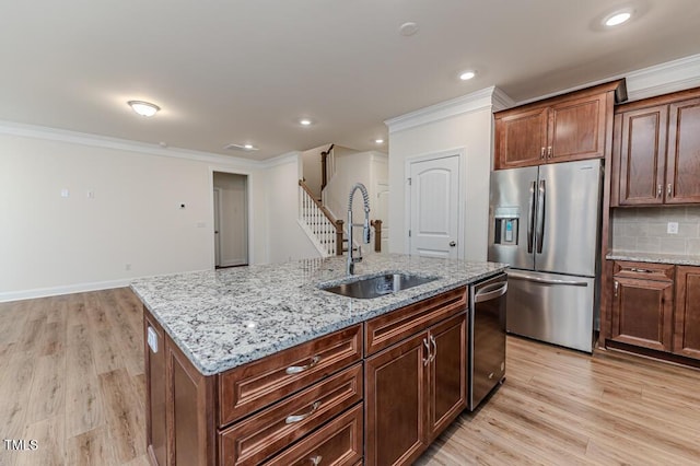 kitchen with stainless steel appliances, an island with sink, crown molding, sink, and tasteful backsplash