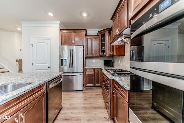 kitchen featuring appliances with stainless steel finishes, crown molding, light stone counters, light hardwood / wood-style flooring, and tasteful backsplash