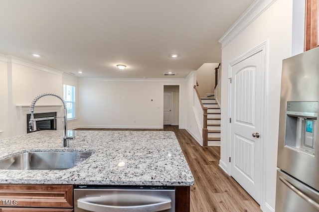 kitchen featuring sink, ornamental molding, light stone counters, and appliances with stainless steel finishes