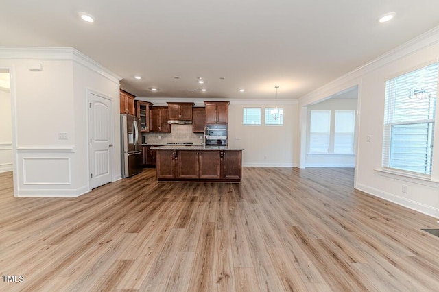 kitchen featuring ornamental molding, light wood-type flooring, stainless steel fridge with ice dispenser, hanging light fixtures, and a kitchen island with sink