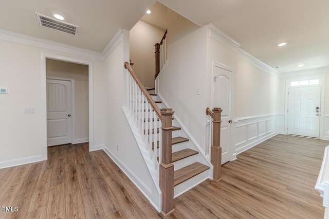 staircase featuring ornamental molding and hardwood / wood-style flooring