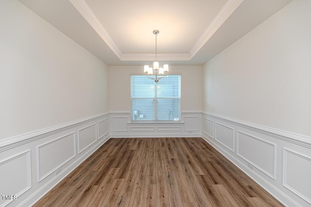 empty room with dark wood-type flooring, a chandelier, and a tray ceiling