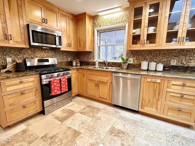 kitchen with appliances with stainless steel finishes, a sink, and backsplash