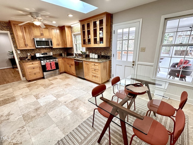 kitchen with a skylight, appliances with stainless steel finishes, backsplash, and a sink