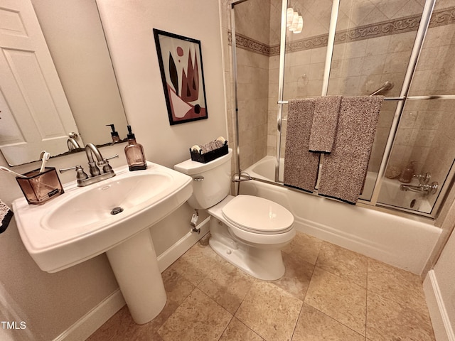 bathroom featuring toilet, shower / bath combination with glass door, and baseboards