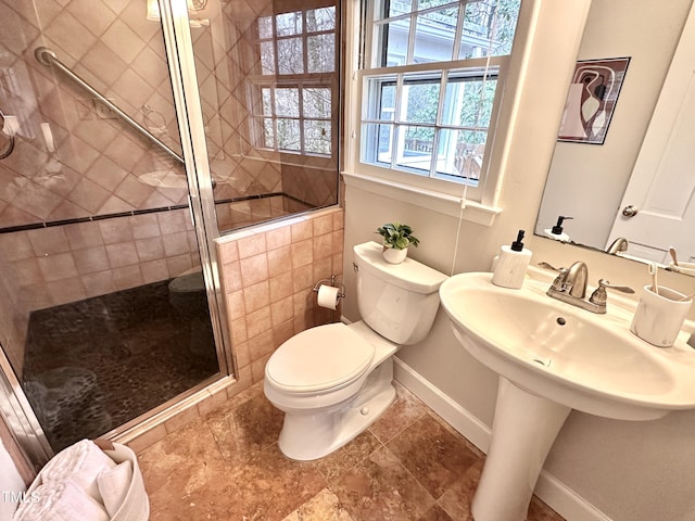 bathroom featuring toilet, a shower stall, and baseboards