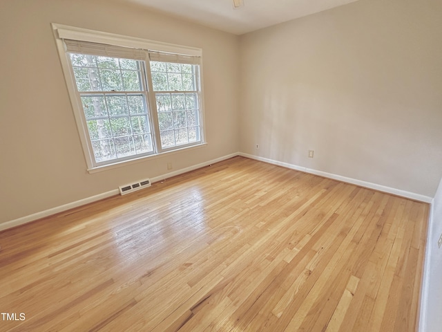 spare room featuring light wood-style flooring, visible vents, and baseboards