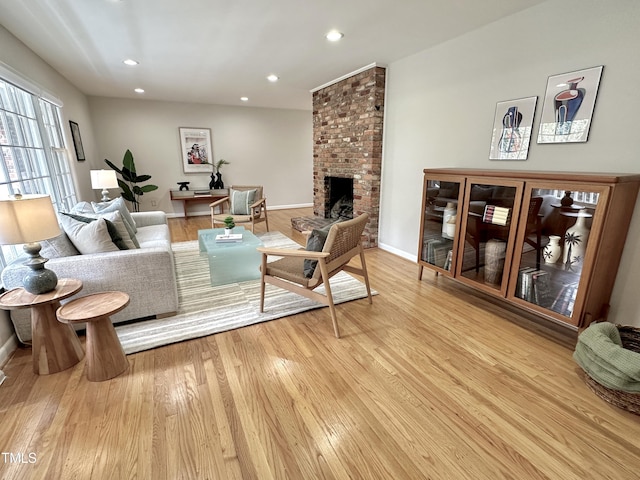 living area with a brick fireplace, light wood-style flooring, baseboards, and recessed lighting