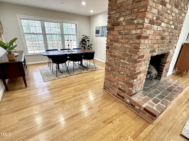 dining area featuring recessed lighting, a brick fireplace, light wood-style flooring, and baseboards