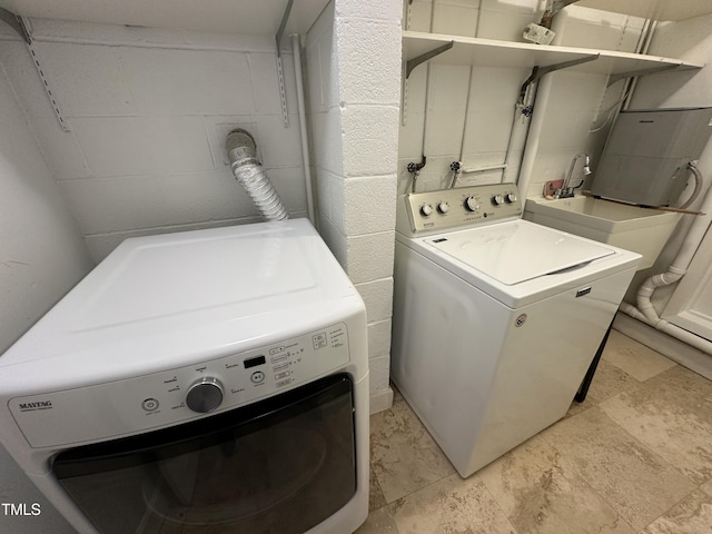 clothes washing area with washer and dryer, laundry area, and concrete block wall