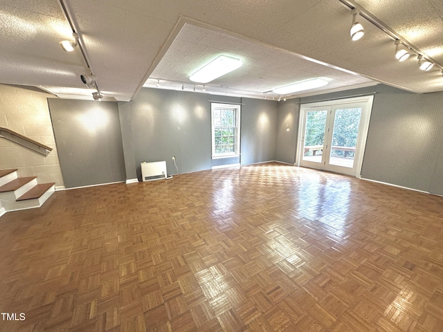 unfurnished room featuring stairway, french doors, a textured ceiling, and track lighting