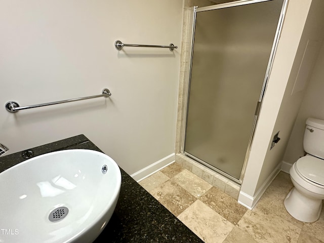 full bathroom featuring a sink, a shower stall, toilet, and baseboards