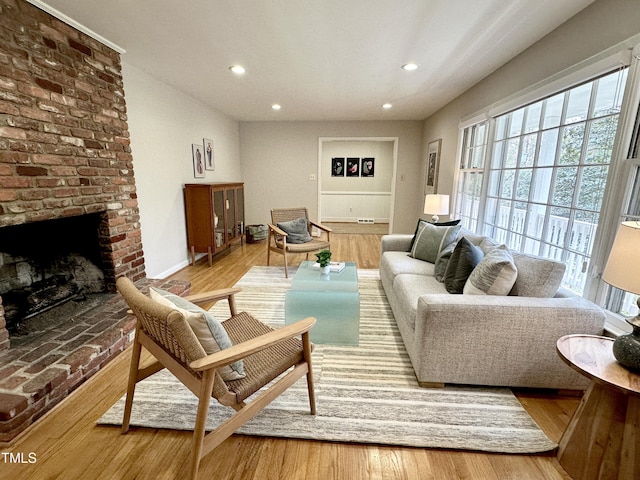 living room with a brick fireplace, wood finished floors, and recessed lighting