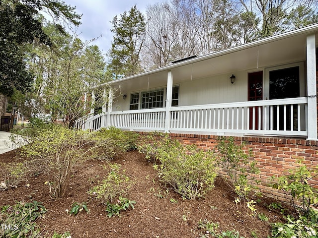 view of property exterior with a porch and brick siding