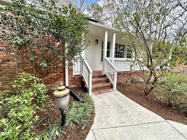 property entrance with a porch and brick siding