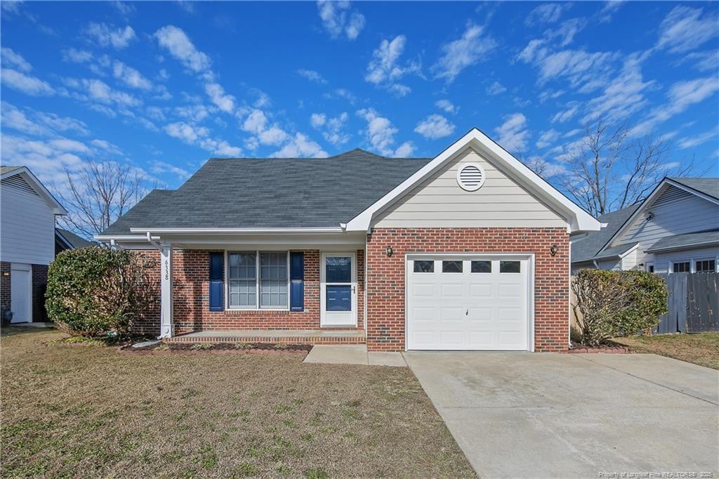 view of front of property with a porch, a front lawn, and a garage