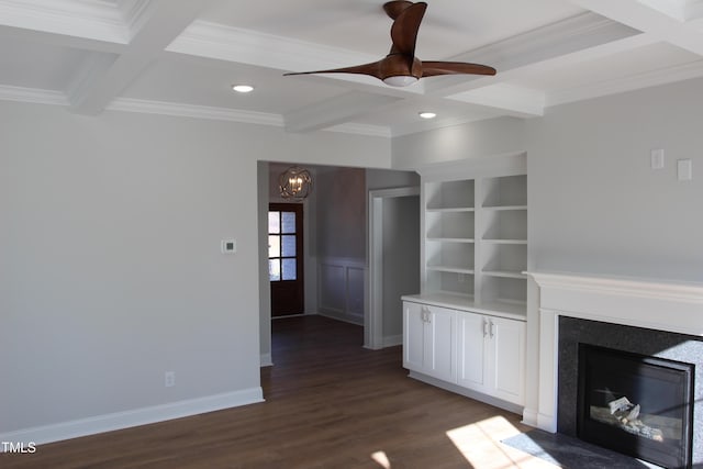 unfurnished living room featuring coffered ceiling, dark hardwood / wood-style floors, built in shelves, ceiling fan with notable chandelier, and beamed ceiling