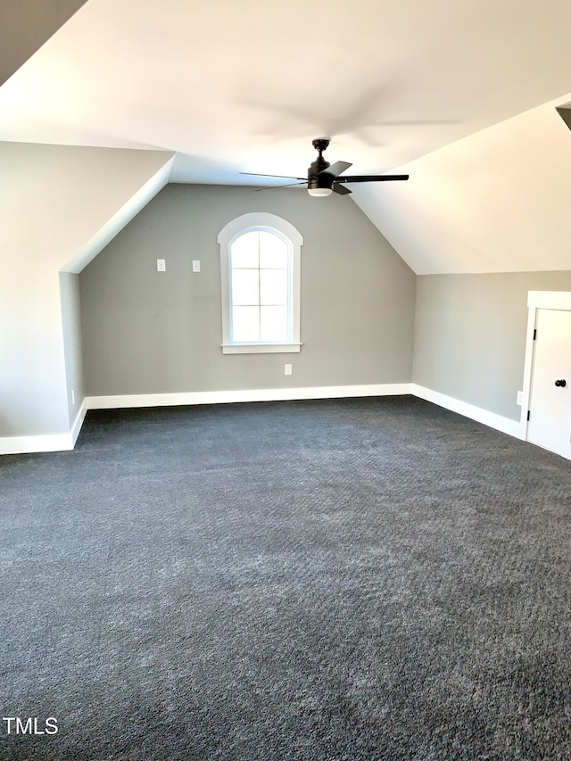 additional living space with ceiling fan, dark colored carpet, and vaulted ceiling