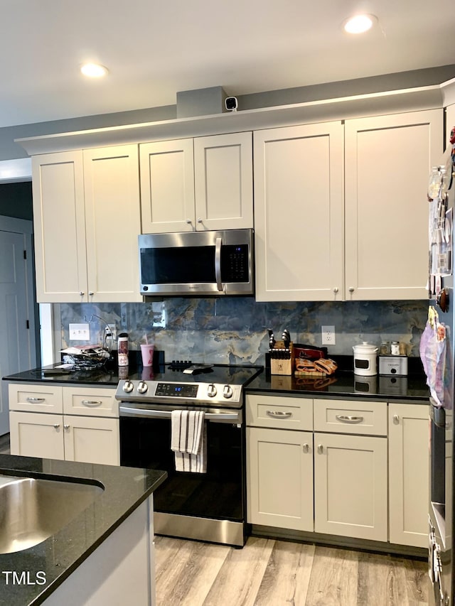 kitchen with white cabinetry, backsplash, appliances with stainless steel finishes, and light wood-type flooring