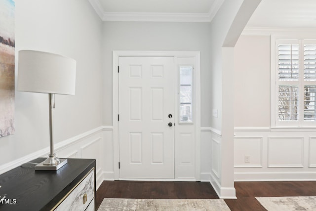 entrance foyer featuring arched walkways, ornamental molding, wainscoting, and dark wood-style flooring