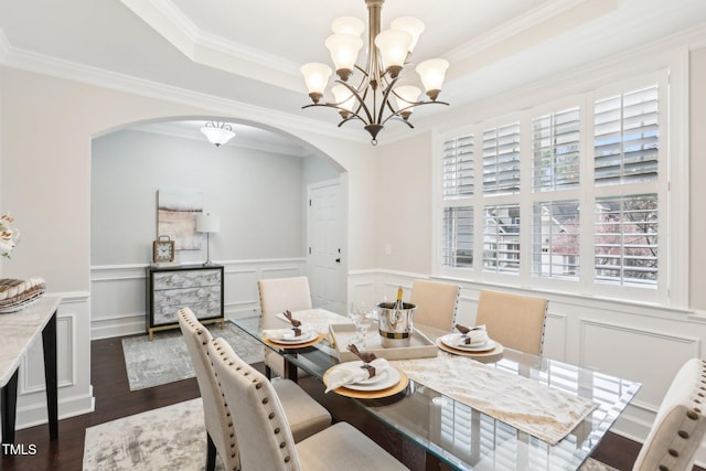 dining area with a tray ceiling, arched walkways, crown molding, a chandelier, and dark wood-style flooring