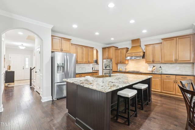 kitchen with custom exhaust hood, dark wood-style floors, arched walkways, and stainless steel appliances