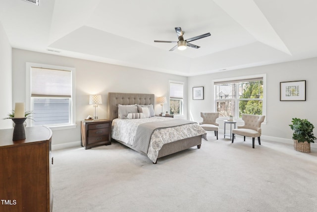 bedroom featuring a raised ceiling, light colored carpet, baseboards, and visible vents