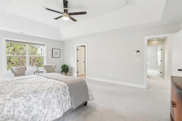 bedroom with visible vents, a tray ceiling, baseboards, light colored carpet, and ceiling fan