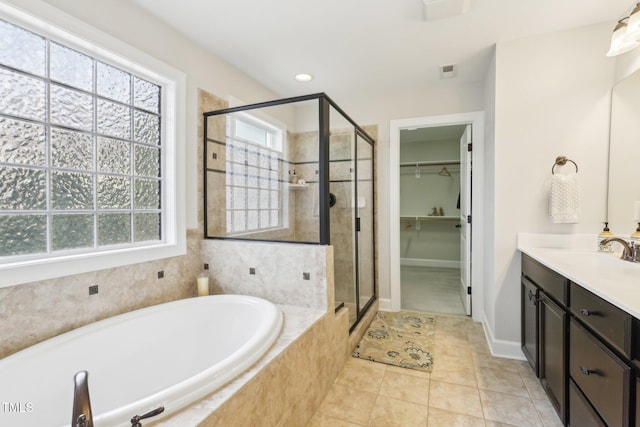 full bathroom with vanity, a stall shower, a spacious closet, a garden tub, and tile patterned floors