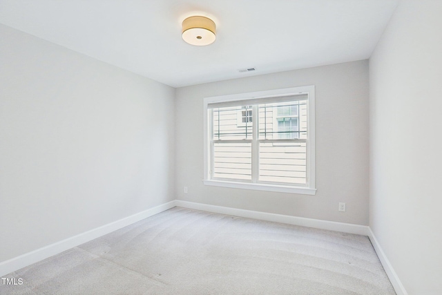 empty room featuring visible vents, light colored carpet, and baseboards