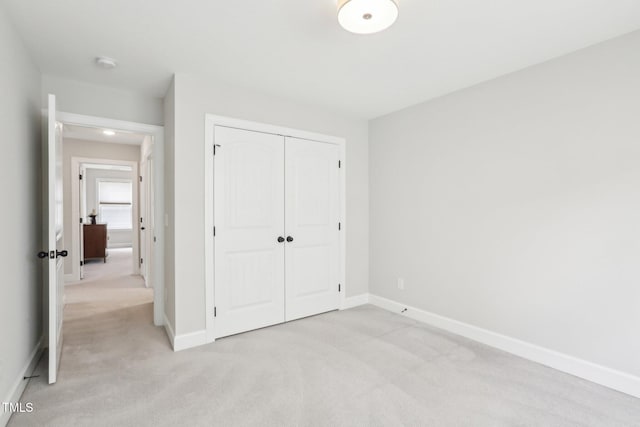 unfurnished bedroom featuring baseboards, light carpet, and a closet