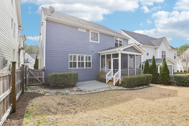 rear view of property with a gate, a patio area, fence, and a sunroom