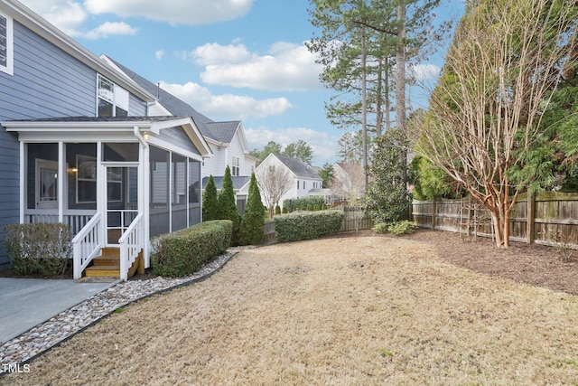 view of yard featuring fence and a sunroom