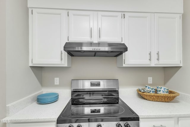 kitchen featuring light stone counters, stainless steel electric stove, and white cabinetry