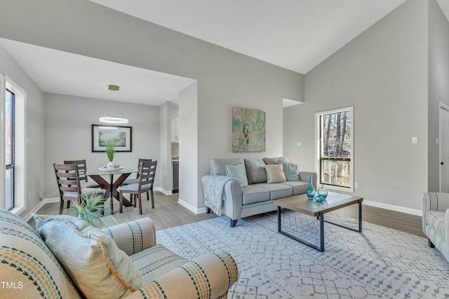 living room featuring a healthy amount of sunlight, light hardwood / wood-style flooring, and lofted ceiling