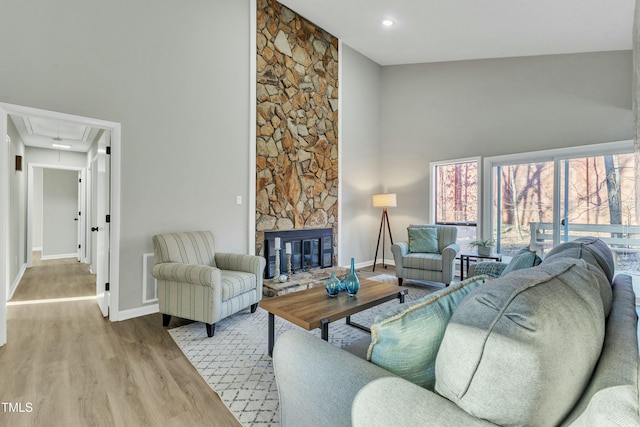 living room featuring a towering ceiling, a fireplace, and light hardwood / wood-style flooring