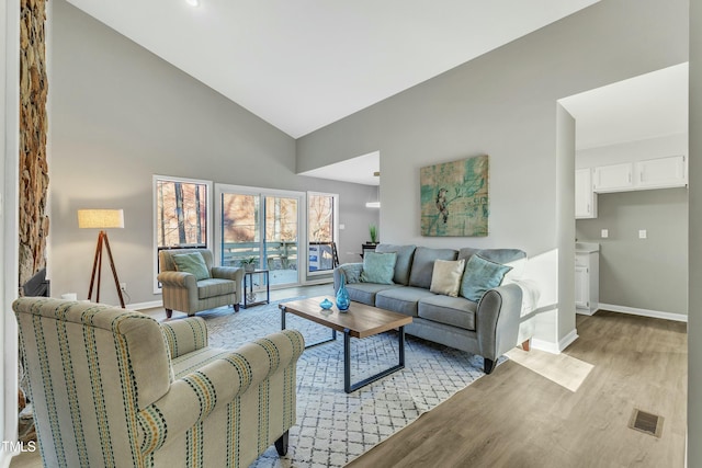 living room with high vaulted ceiling and light hardwood / wood-style flooring