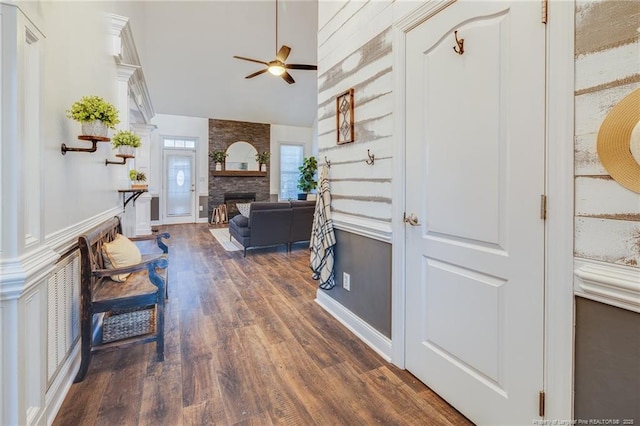 foyer entrance with ceiling fan, lofted ceiling, dark hardwood / wood-style floors, and a fireplace