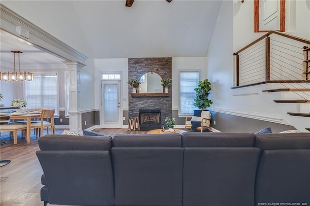 living room featuring a healthy amount of sunlight, a stone fireplace, decorative columns, and wood-type flooring