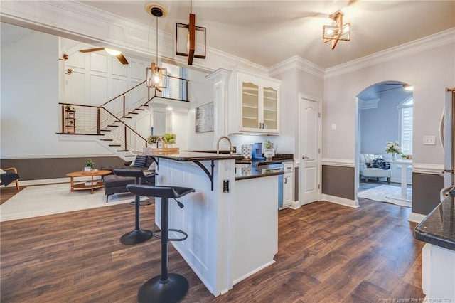 kitchen with decorative light fixtures, white cabinets, dark hardwood / wood-style flooring, and a kitchen bar