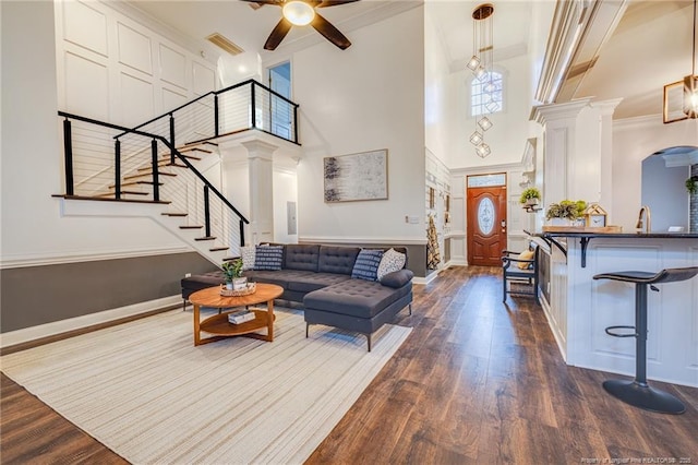 living room with a high ceiling, dark hardwood / wood-style flooring, ornamental molding, and plenty of natural light