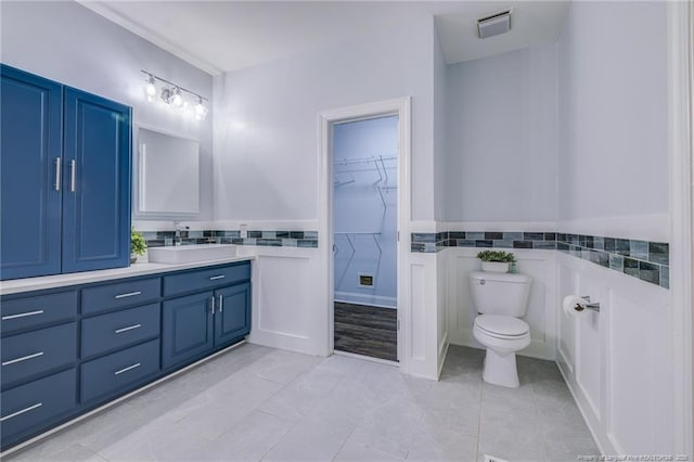 bathroom with toilet, tile patterned flooring, vanity, and tile walls