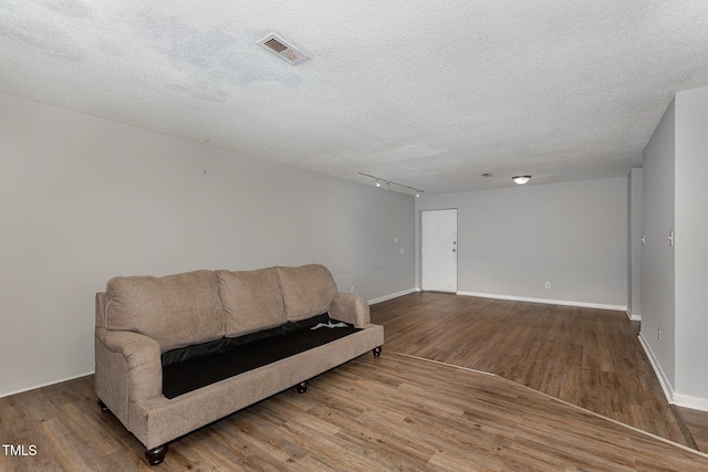 living area with a textured ceiling, rail lighting, and hardwood / wood-style flooring